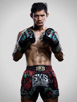 Suablack, a male Muay Thai fighter from Thailand, poses in Red SKS hand wrap and black SKS Muay Thai shorts with many sakyant patterns, showcasing his athletic build and traditional Thai boxing gear.